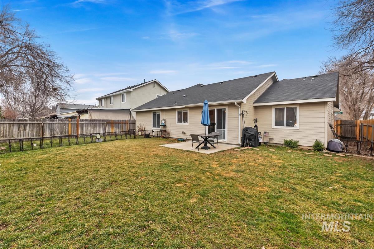 Rear view of house with a patio, roof with shingles, and a fenced backyard