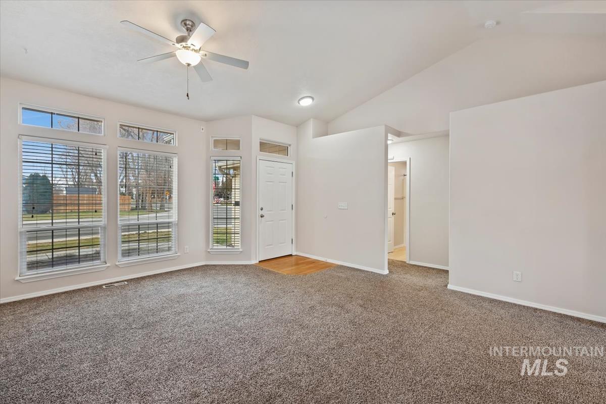 Unfurnished room with light colored carpet, a ceiling fan, and lofted ceiling