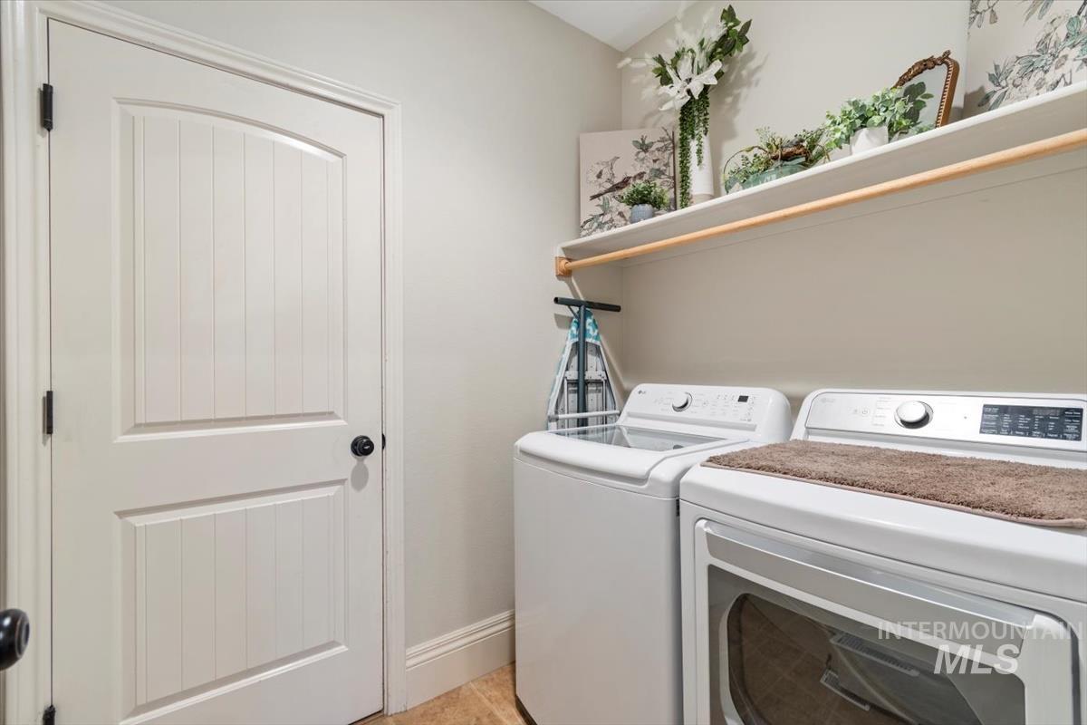 Laundry room with separate washer and dryer and light tile patterned floors