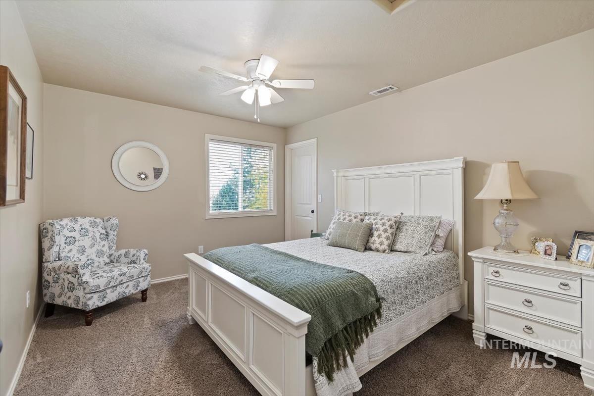 Bedroom with dark colored carpet and ceiling fan