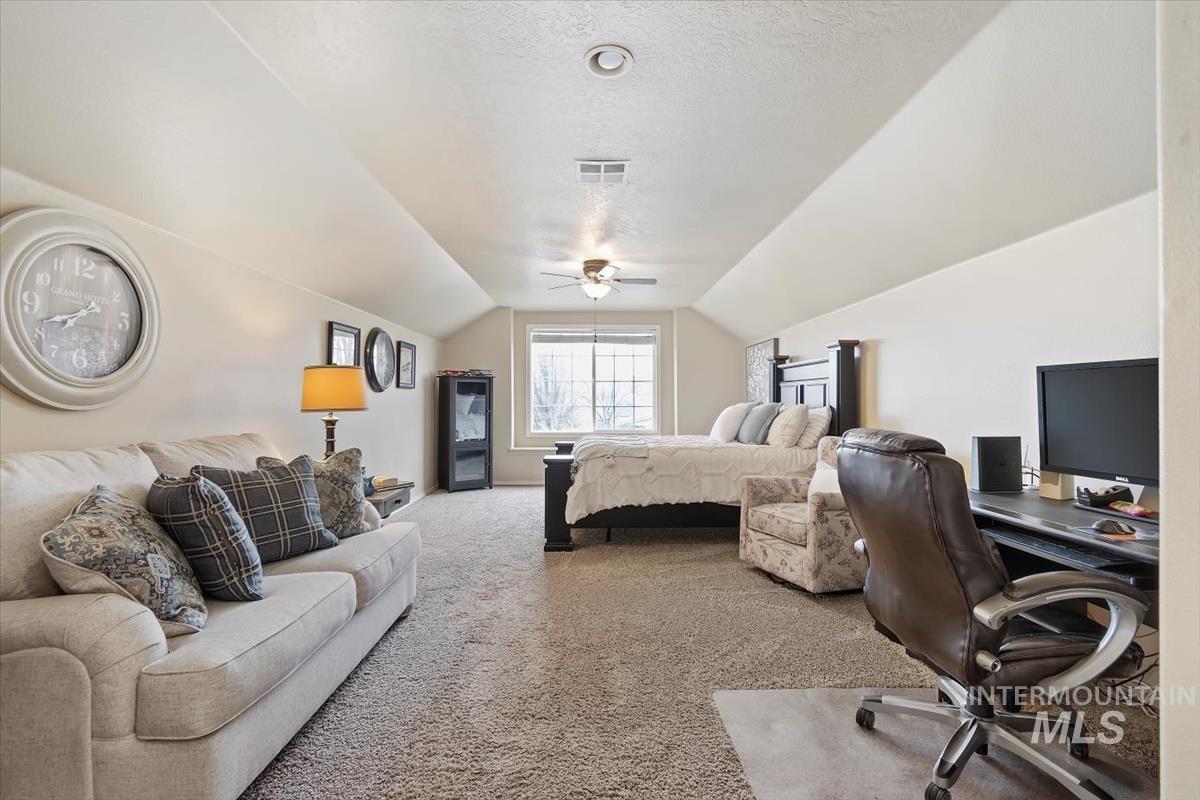 Carpeted bedroom with a textured ceiling, an office area, lofted ceiling, a ceiling fan, and access to outside