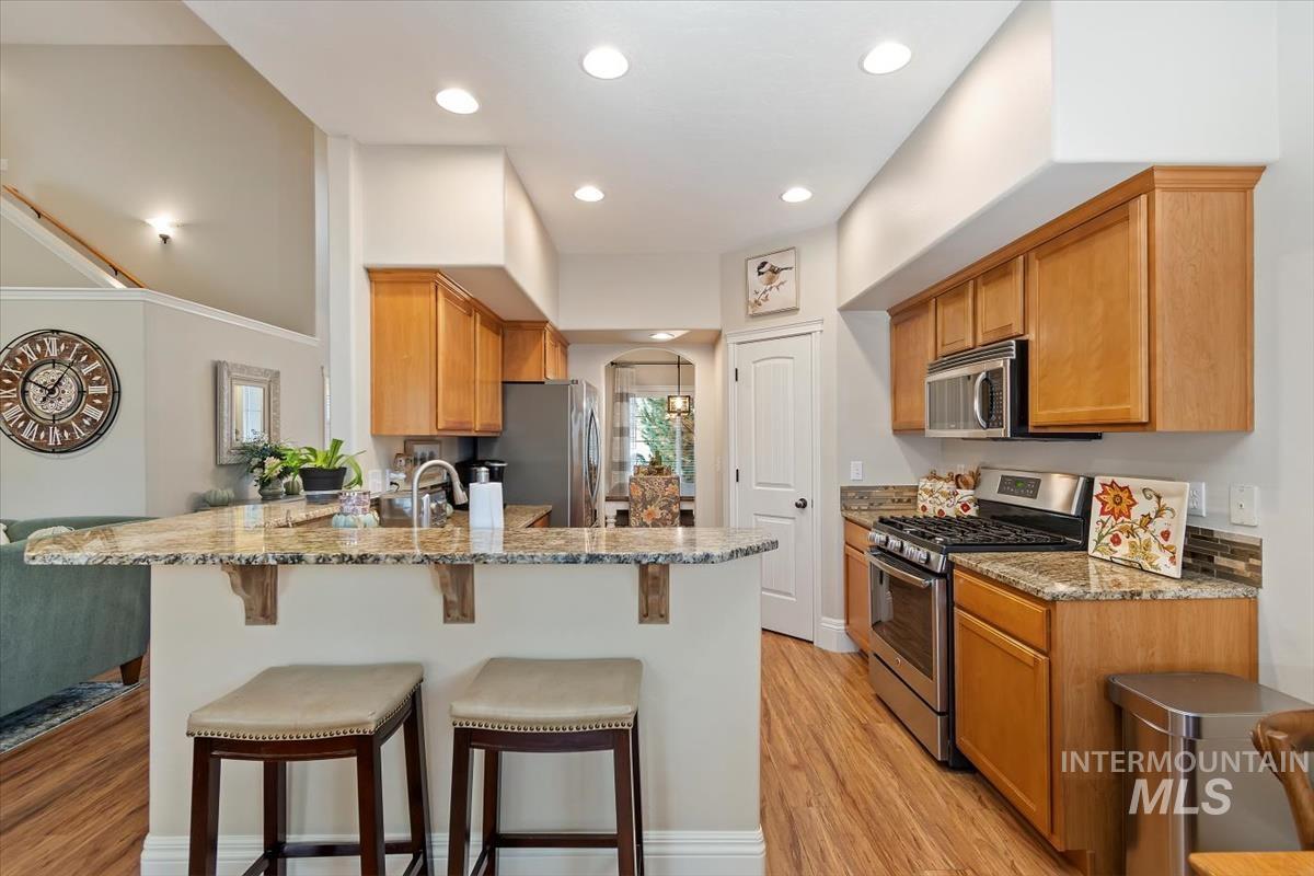 Kitchen with stainless steel appliances, arched walkways, a peninsula, a breakfast bar, and light stone countertops
