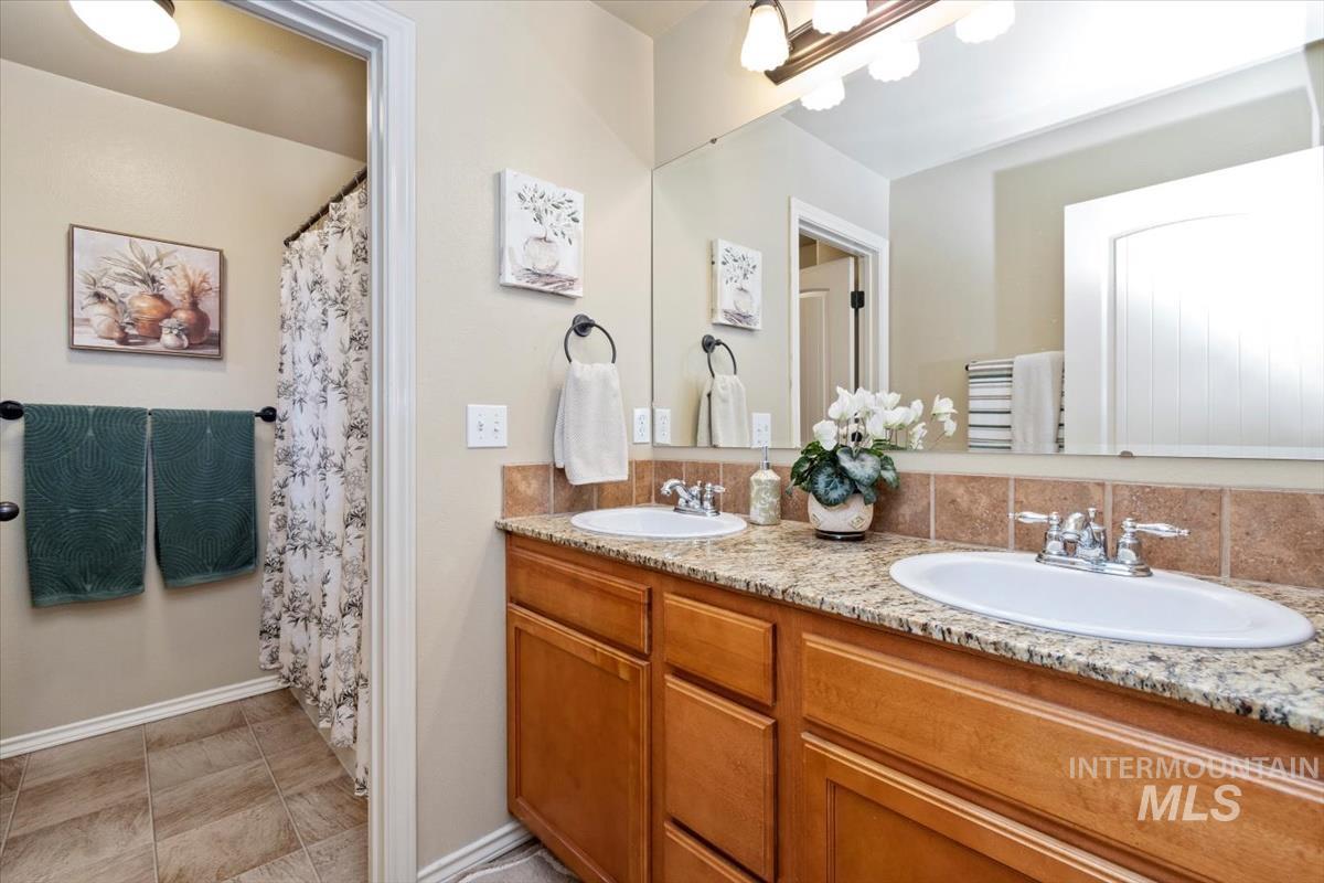 Full bath with curtained shower and double vanity