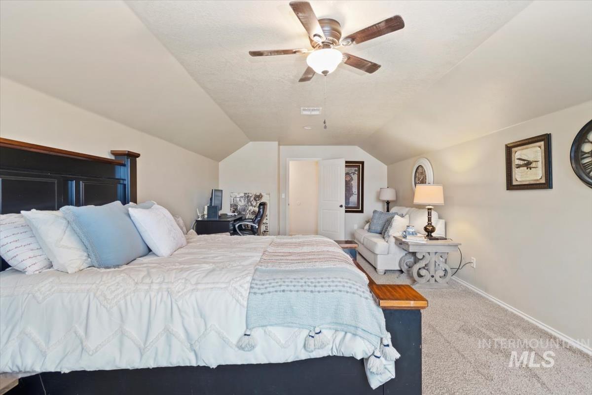 Bedroom with carpet, lofted ceiling, ceiling fan, and a textured ceiling