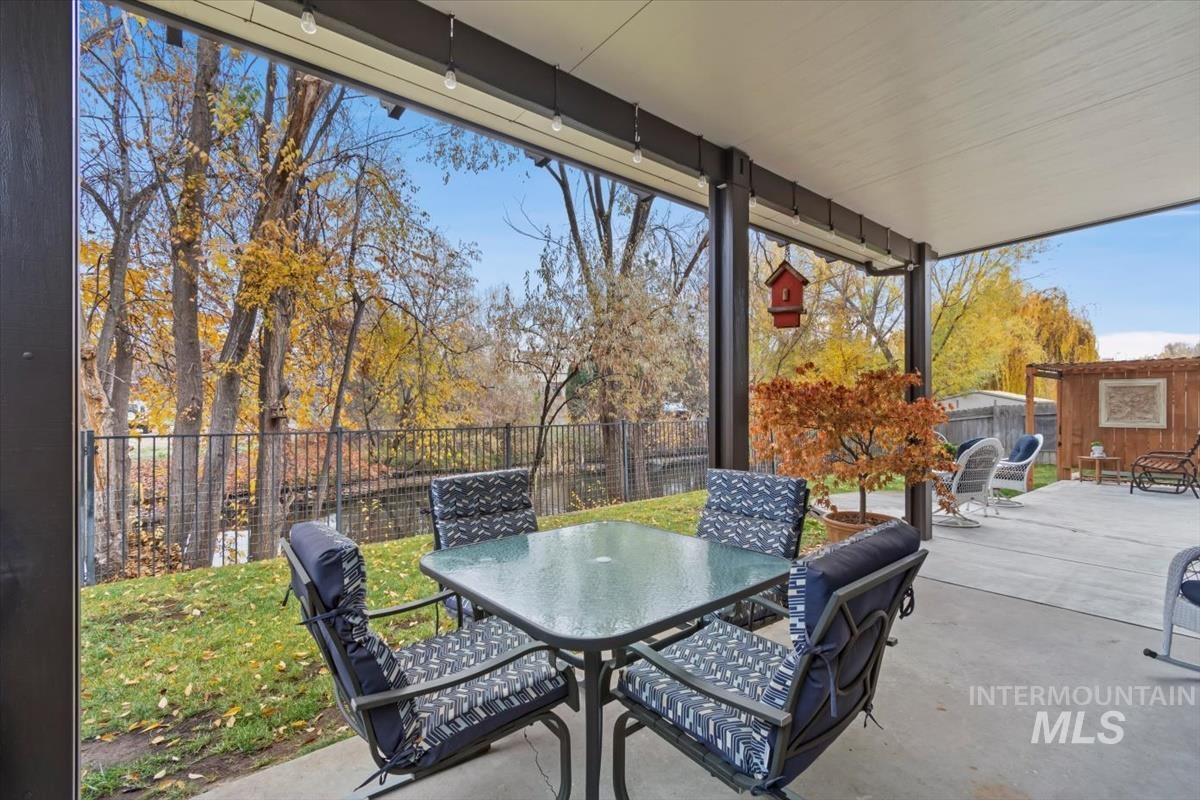 Fenced backyard featuring outdoor dining area, a patio, and an outbuilding