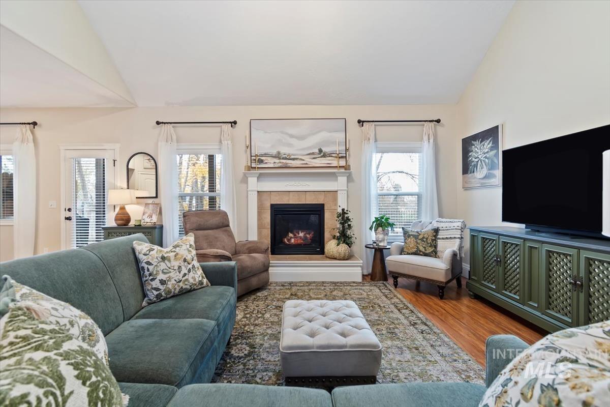 Living room featuring vaulted ceiling, wood finished floors, and a tiled fireplace