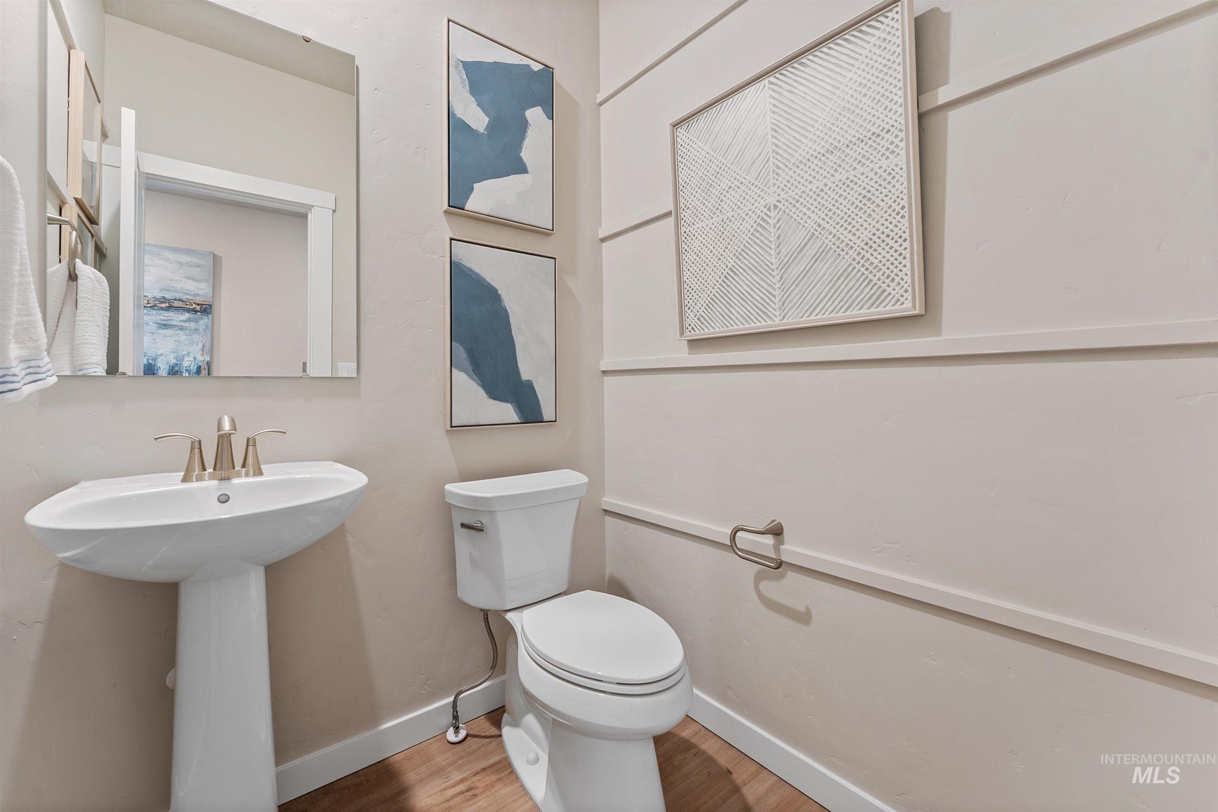 Half bathroom with toilet and wood finished floors