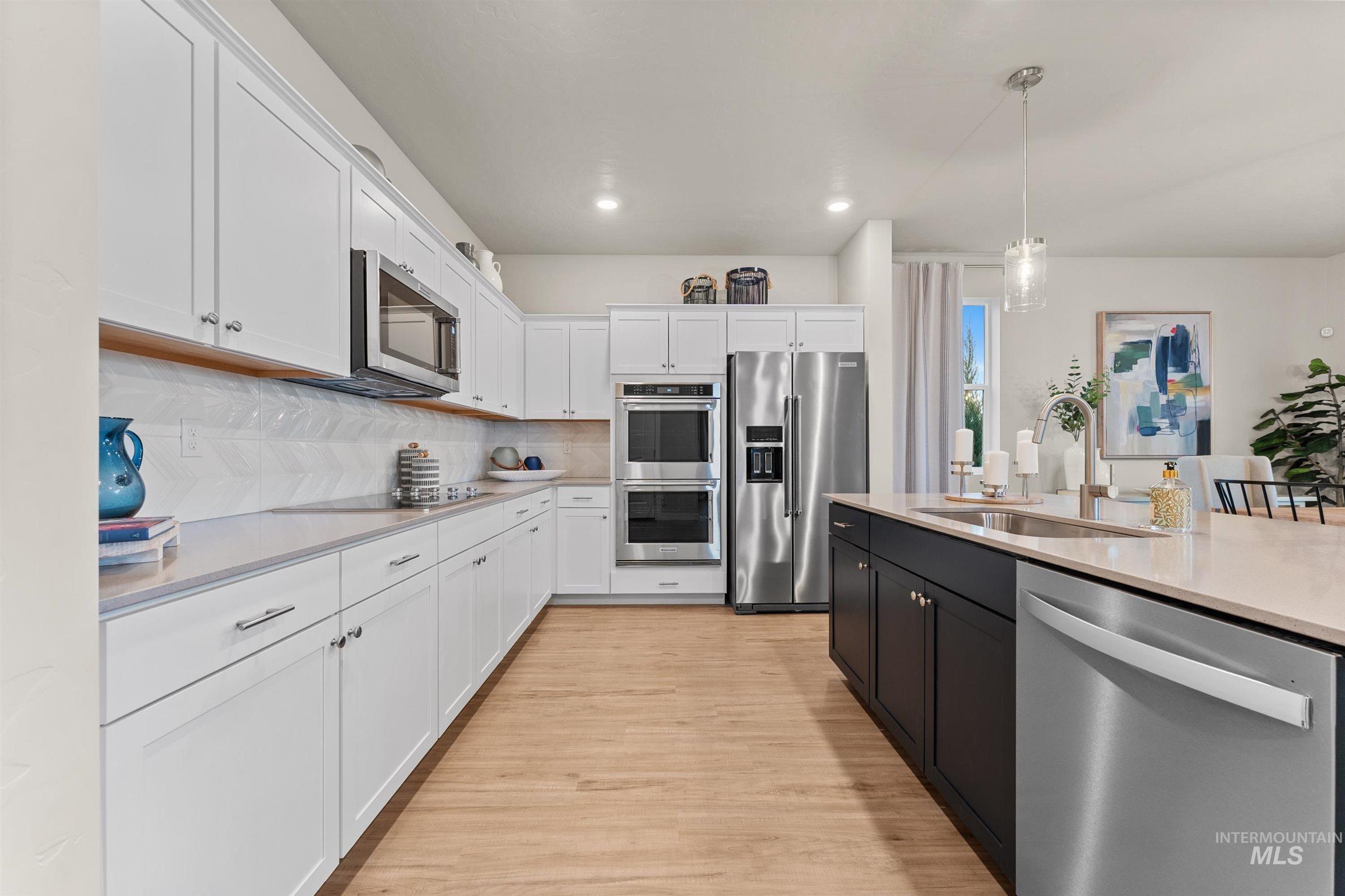 Kitchen with appliances with stainless steel finishes, decorative light fixtures, white cabinetry, backsplash, and recessed lighting