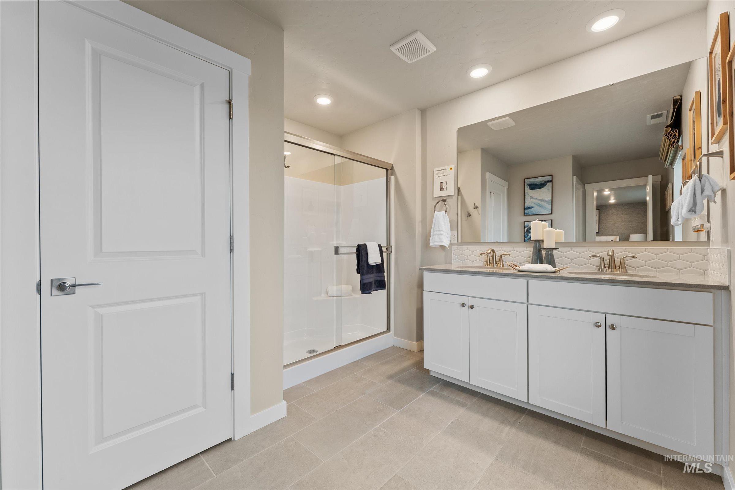 Full bathroom with decorative backsplash, double vanity, a shower stall, recessed lighting, and light tile patterned floors