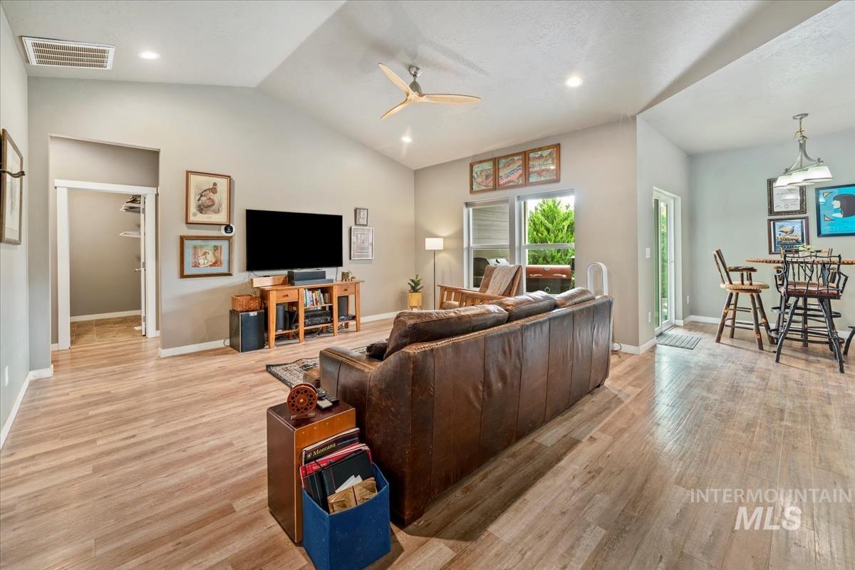 Living area featuring lofted ceiling, light wood finished floors, a ceiling fan, and recessed lighting