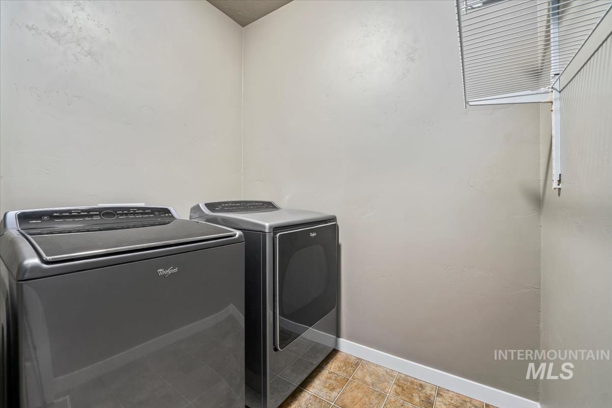 Laundry area featuring washing machine and dryer and light tile patterned floors