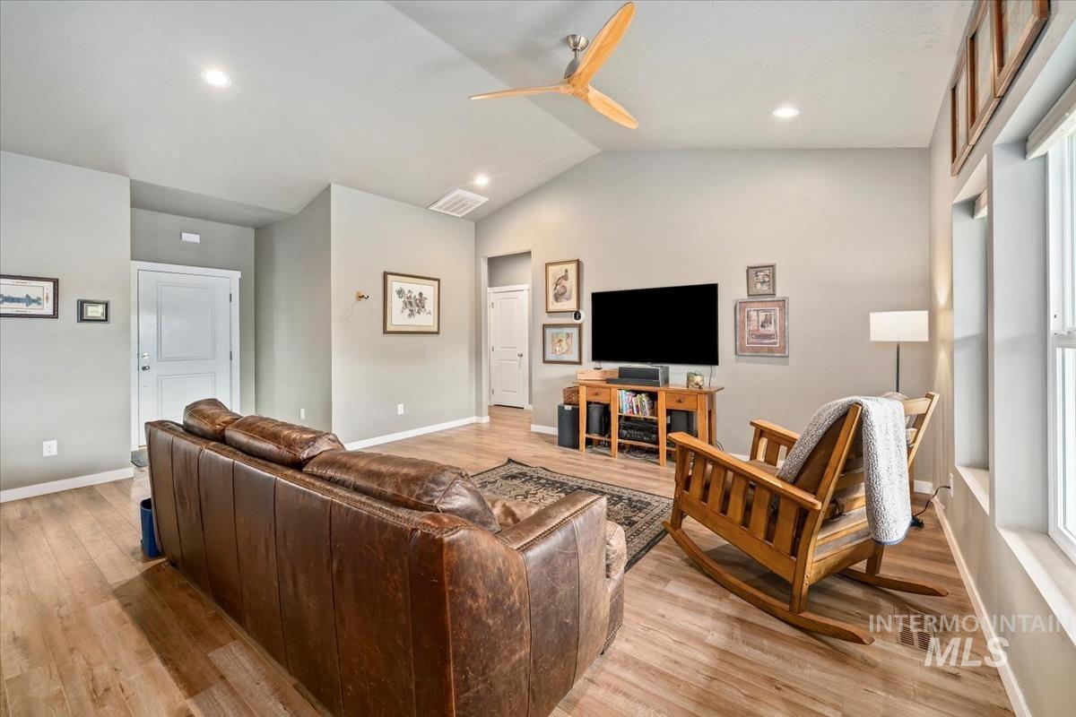 Living area with vaulted ceiling, light wood-style floors, a ceiling fan, and recessed lighting