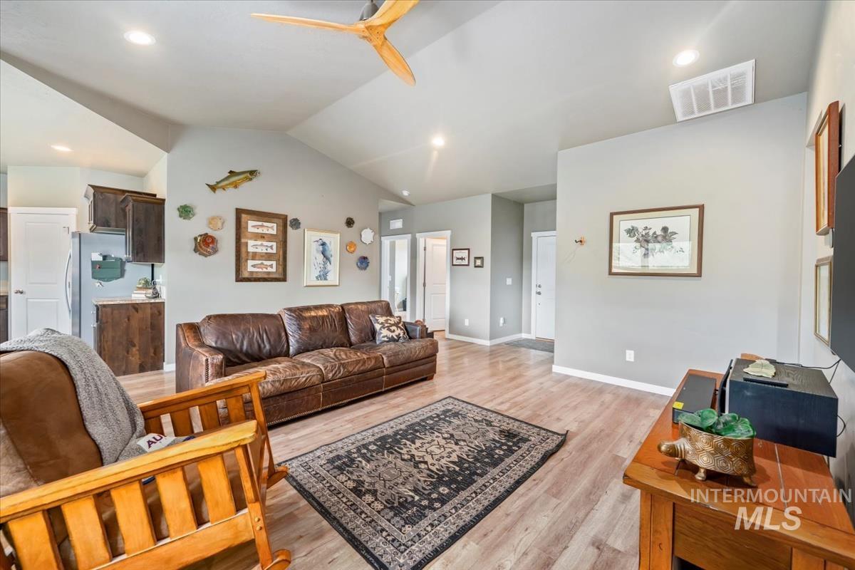 Living room with lofted ceiling, light wood-type flooring, ceiling fan, and recessed lighting