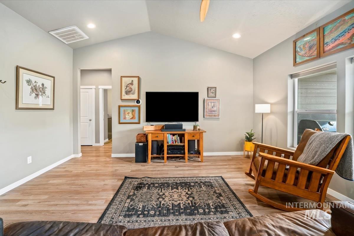 Living room featuring vaulted ceiling, light wood-style floors, and recessed lighting