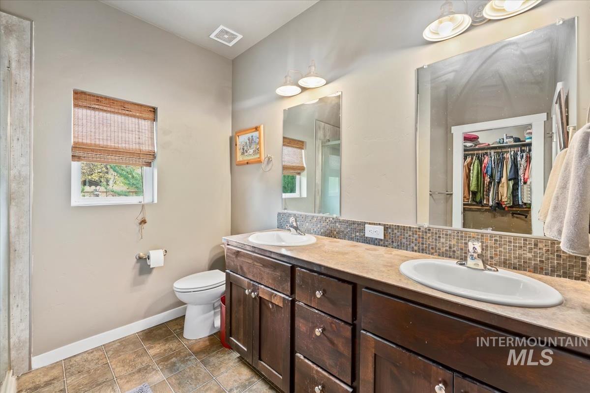 Full bathroom featuring tasteful backsplash, a stall shower, double vanity, and plenty of natural light