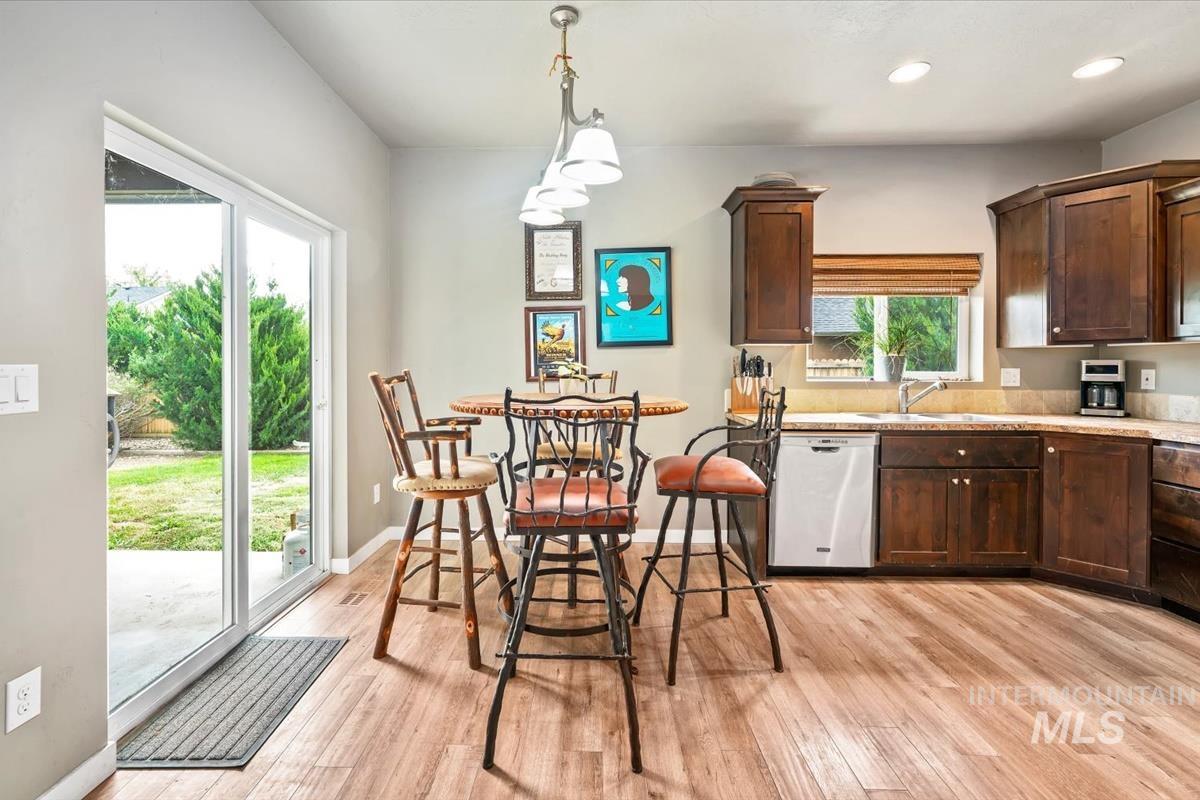 Kitchen with dark brown cabinets, decorative light fixtures, dishwasher, light wood-style floors, and recessed lighting