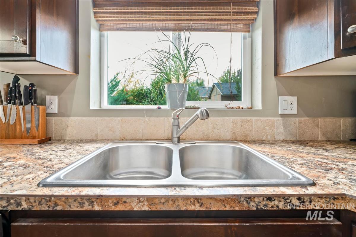 Kitchen view of a sink and dark brown cabinetry