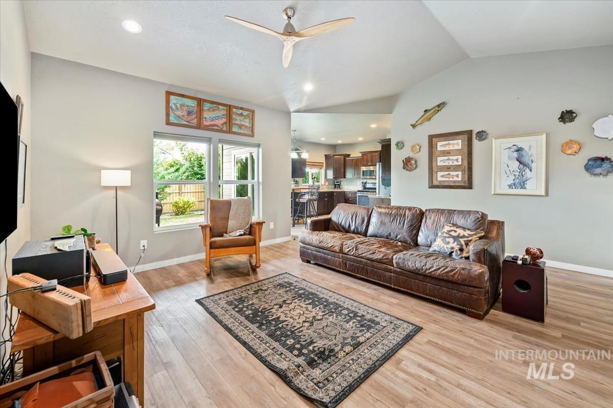 Living area with lofted ceiling, recessed lighting, ceiling fan, and light wood-style floors