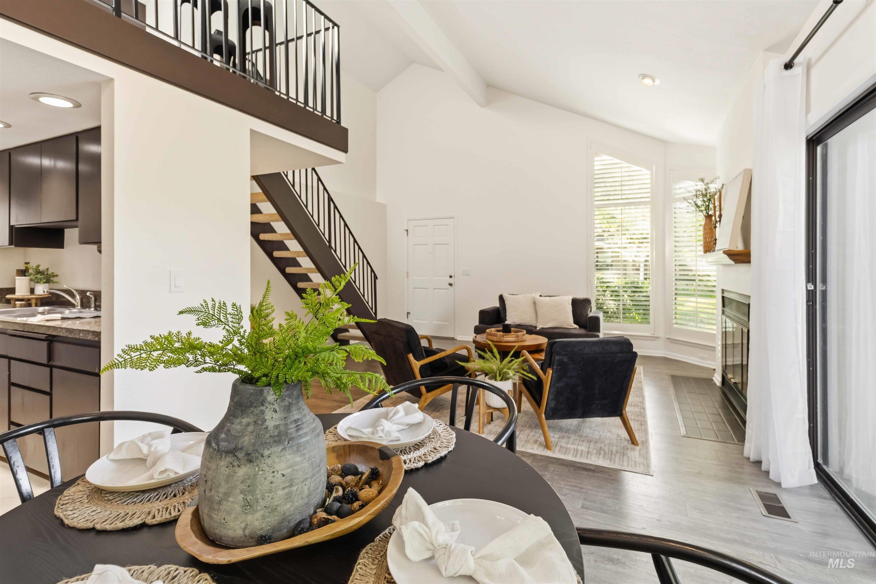 Vaulted living area with wood-finish flooring, a fireplace, and large windows