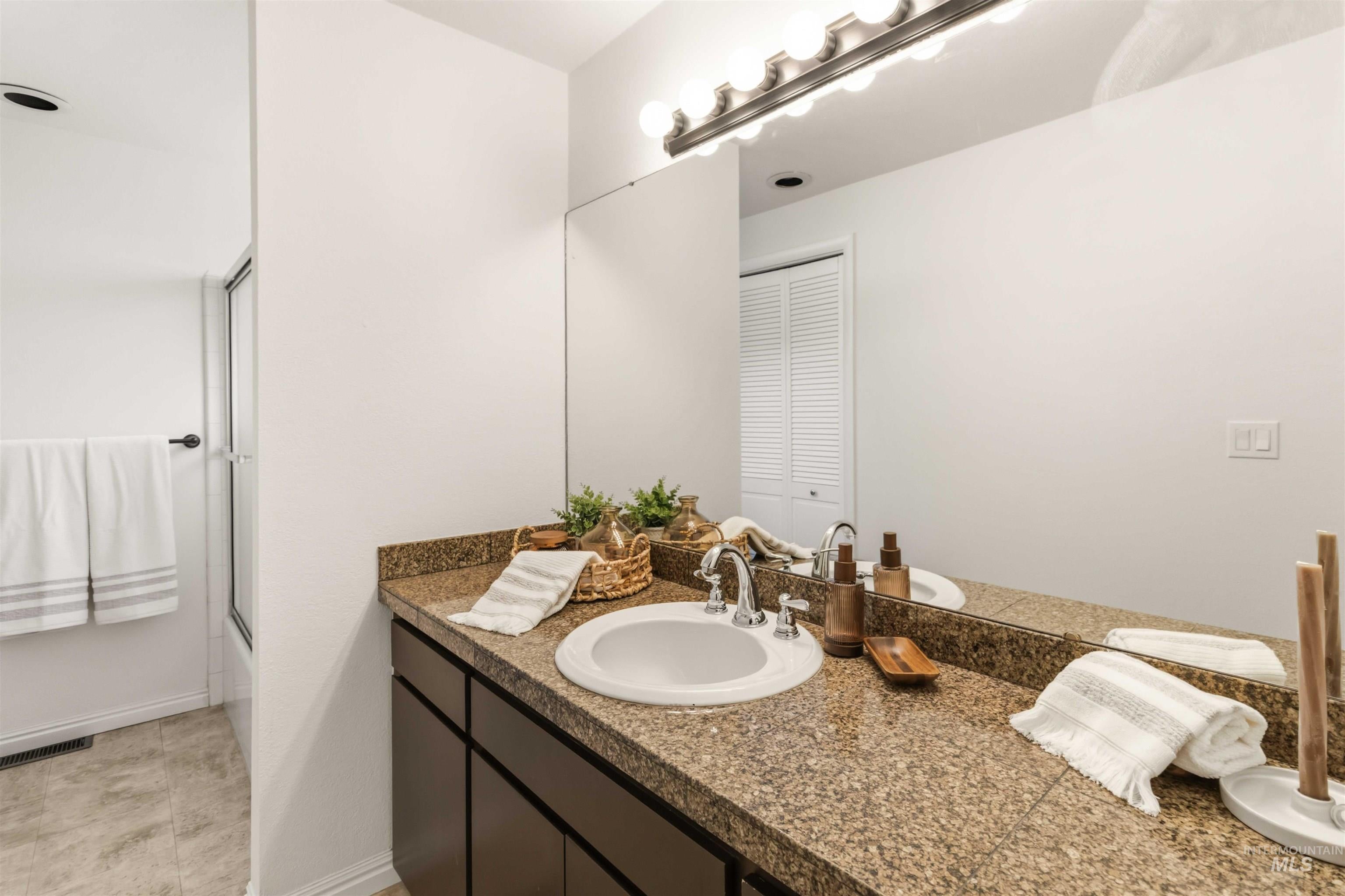 Bathroom featuring a spacious vanity with a granite-style countertop and an integrated sink