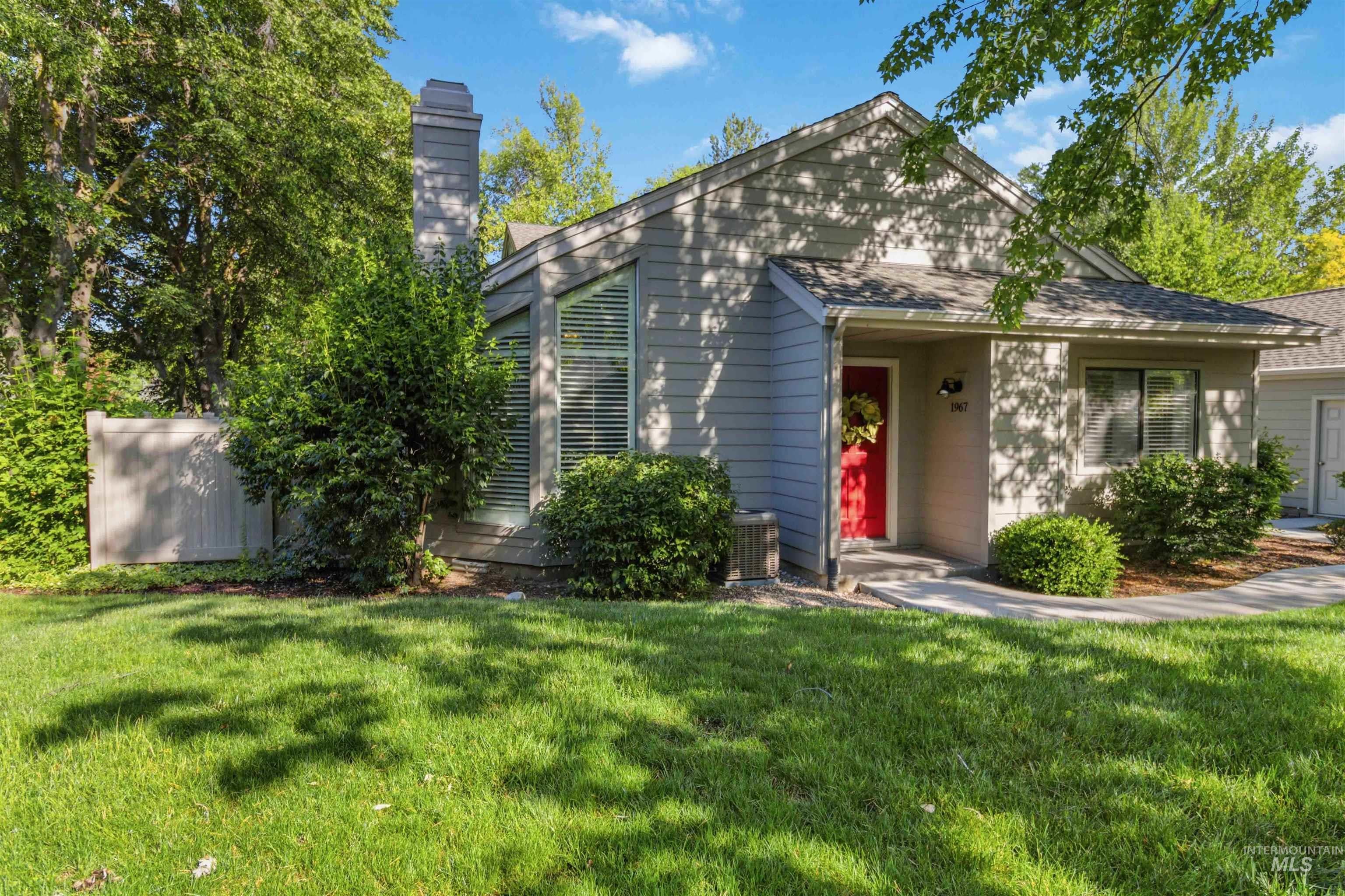 Light grey siding exterior with a vibrant red entry door