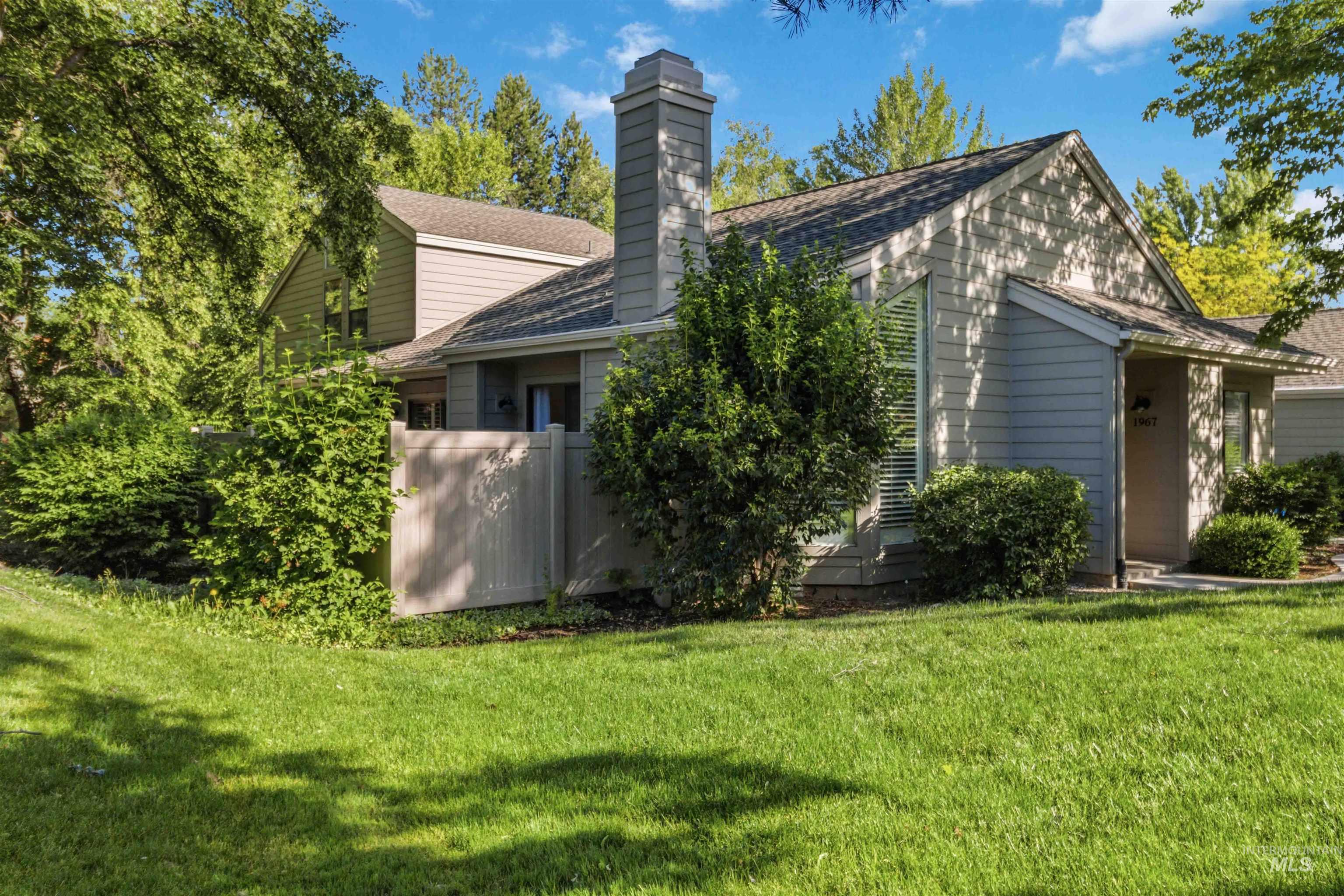 Exterior featuring light-toned siding, a prominent chimney, and a gabled roofline