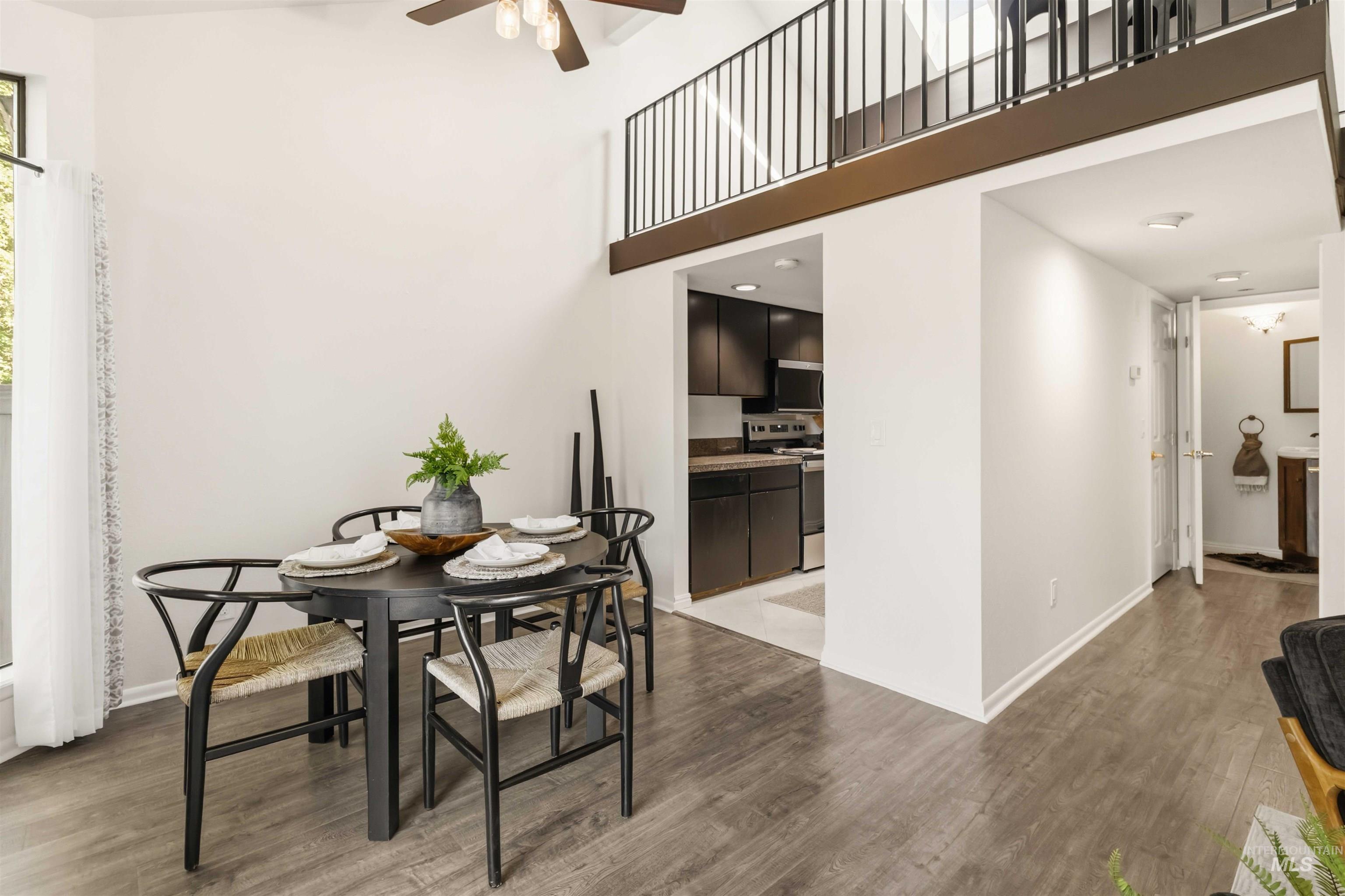 Open-concept dining area featuring vaulted ceilings, wood-finish flooring, and a ceiling fan