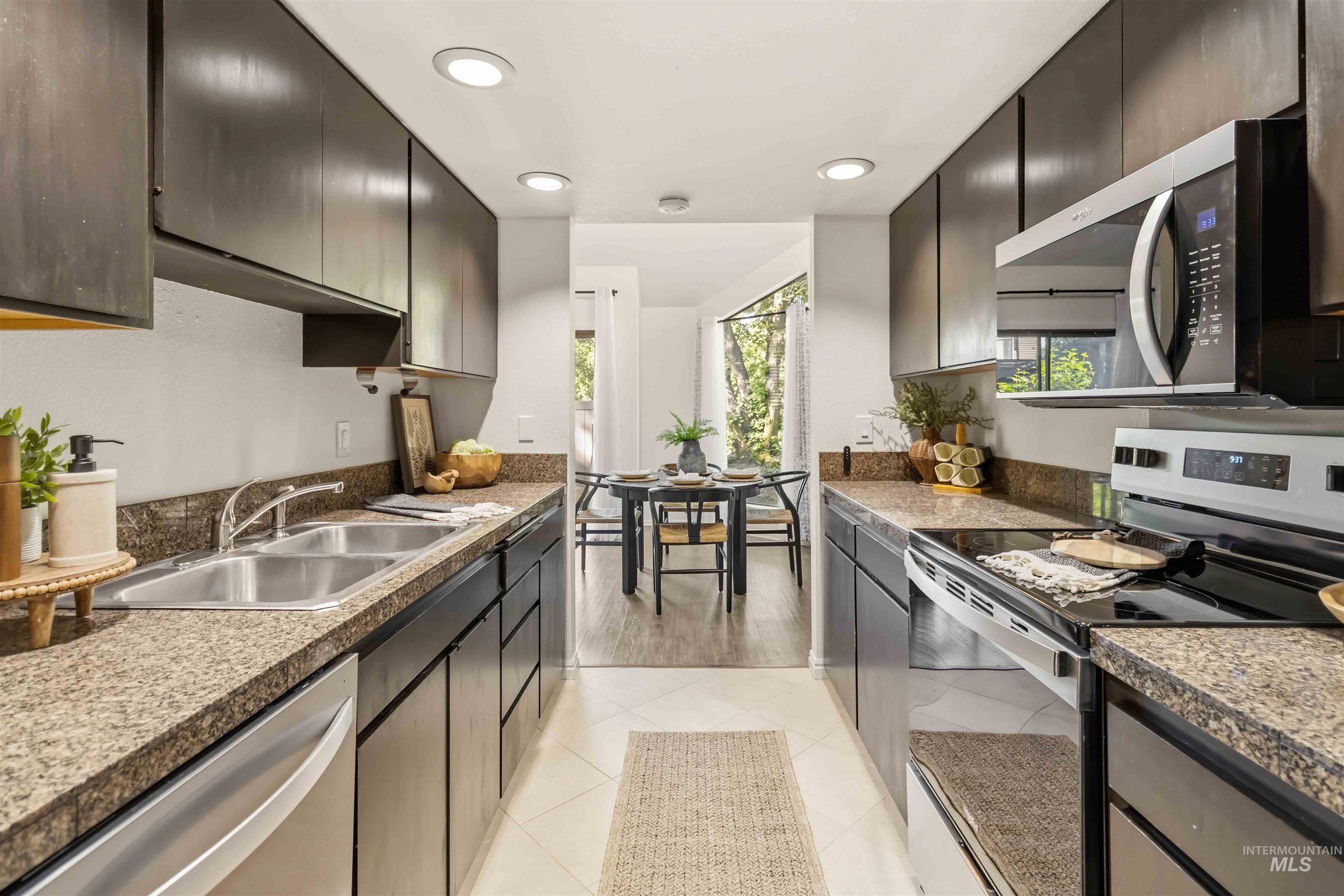 Galley-style kitchen featuring dark wood-finish cabinetry, speckled countertops, and recessed lighting