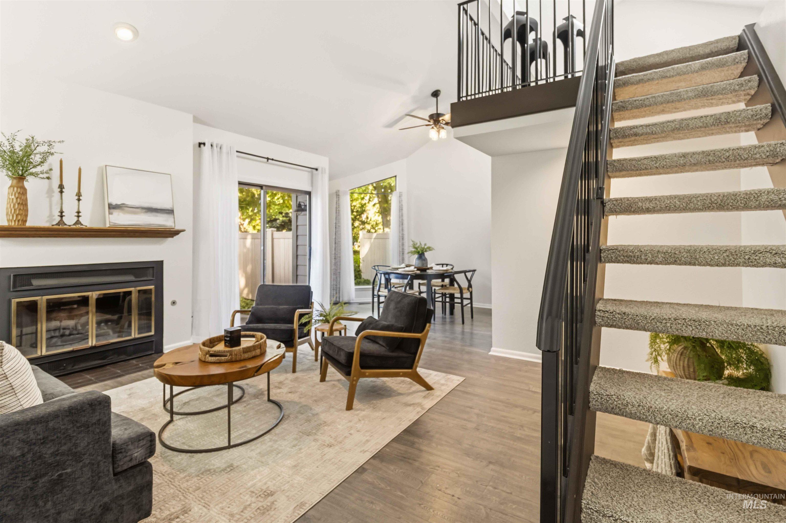 Carpeted staircase with black iron railing, wood-finish flooring, and a fireplace featuring a wood mantel