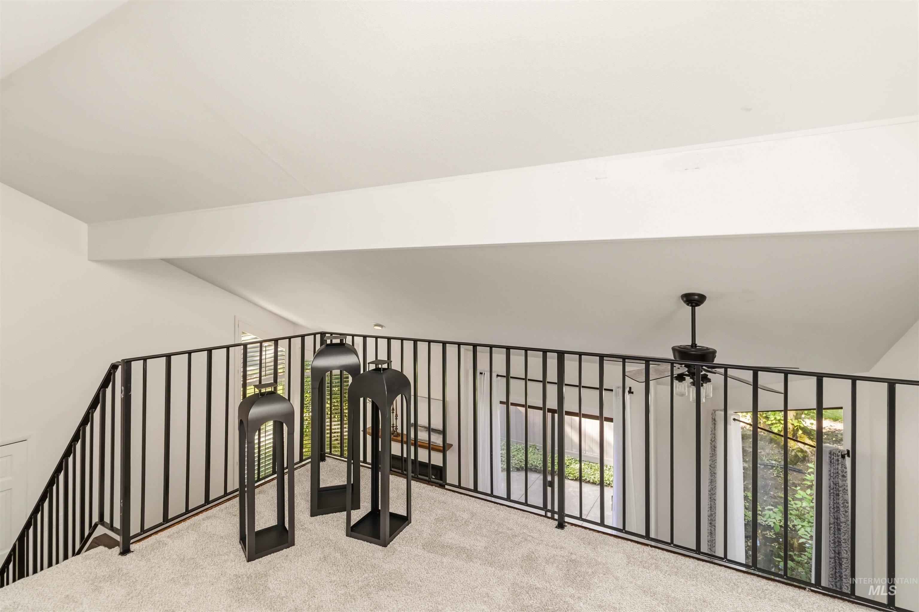 Loft space featuring a prominent skylight, light-colored carpeting, fresh painted walls, a dark ceiling beam