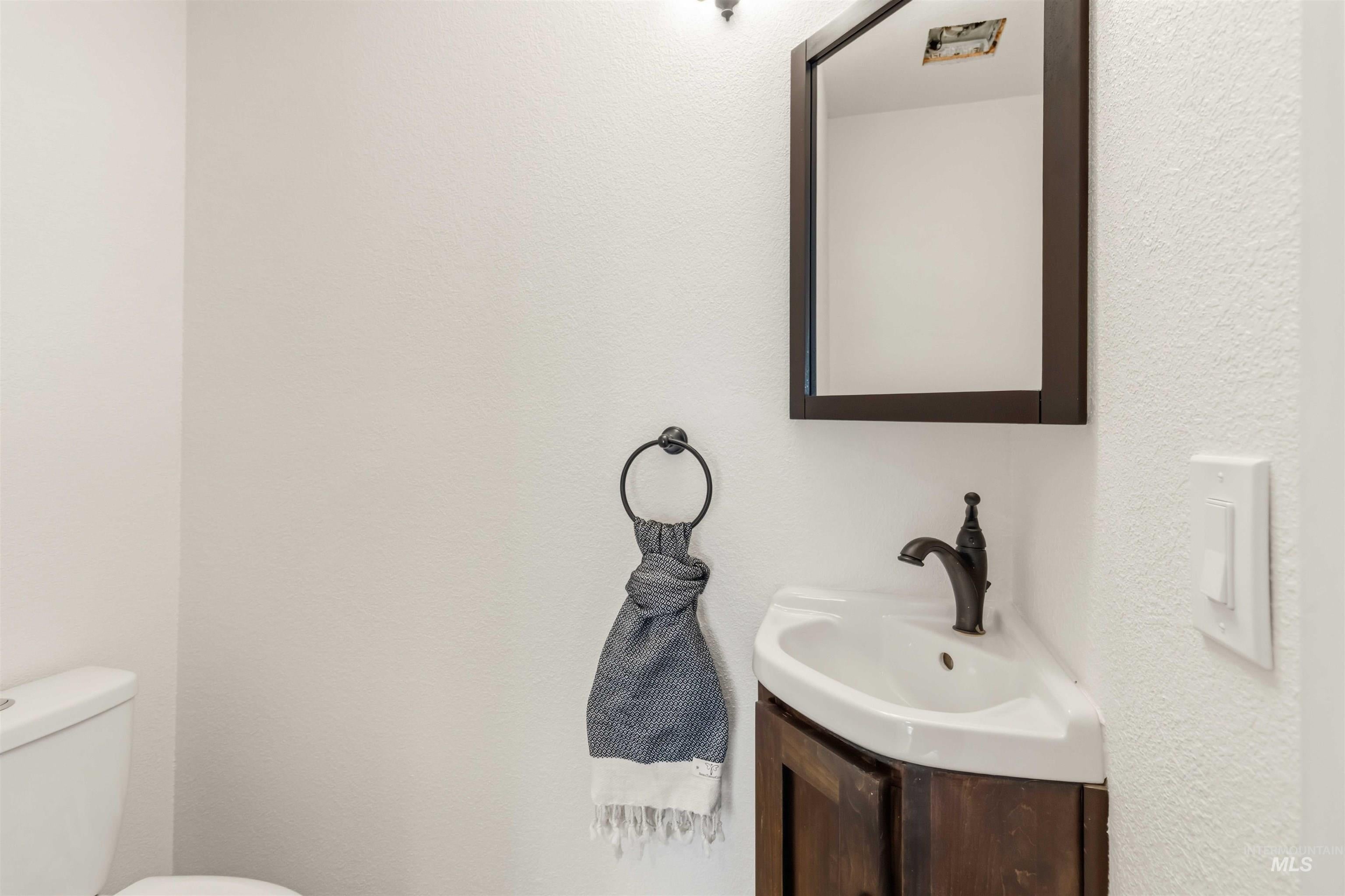 Corner vanity with an integrated sink and dark wood-finish cabinetry, complemented by a framed mirror and oil-rubbed bronze faucet