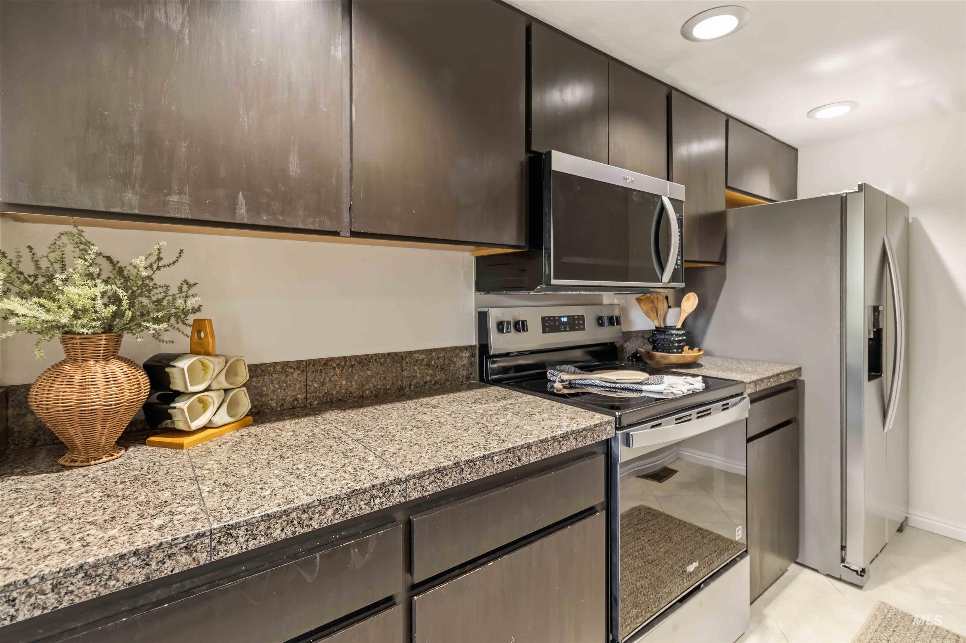 Kitchen featuring dark cabinetry with light-colored countertops, stainless steel appliances, and recessed lighting
