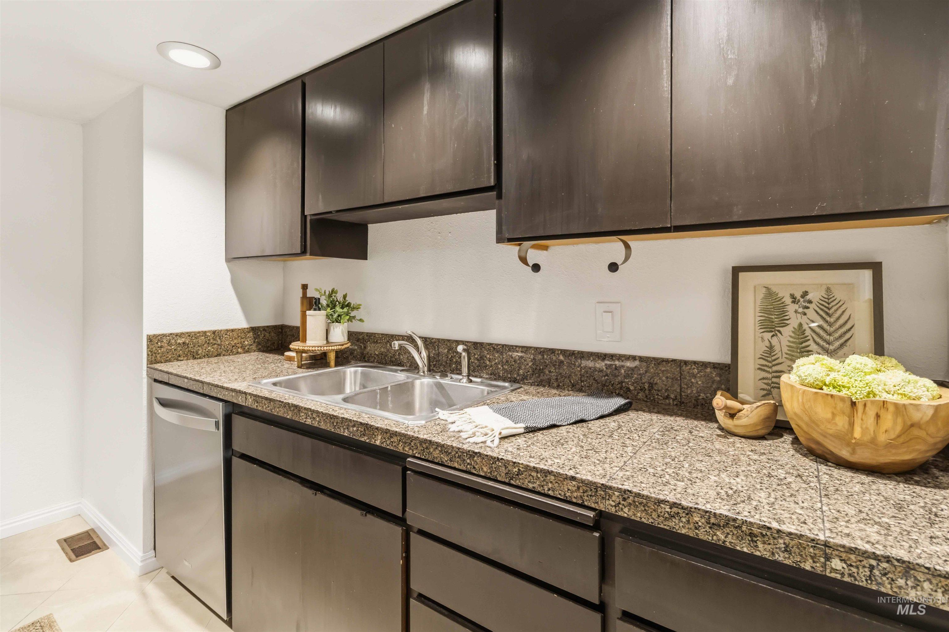 Kitchen featuring dark wood-finish cabinetry, granite countertops, and a double basin stainless steel sink