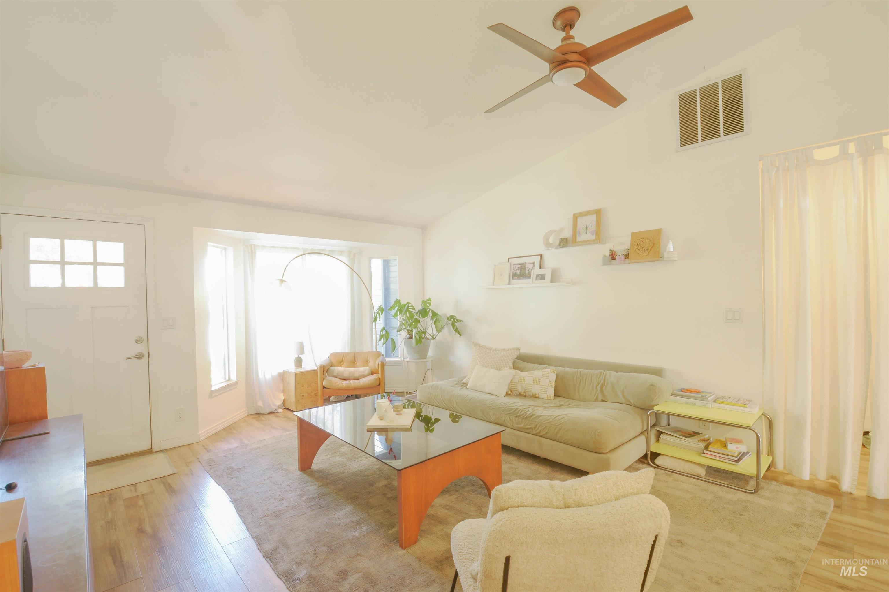 Living area featuring plenty of natural light, light wood-style floors, a ceiling fan, and high vaulted ceiling