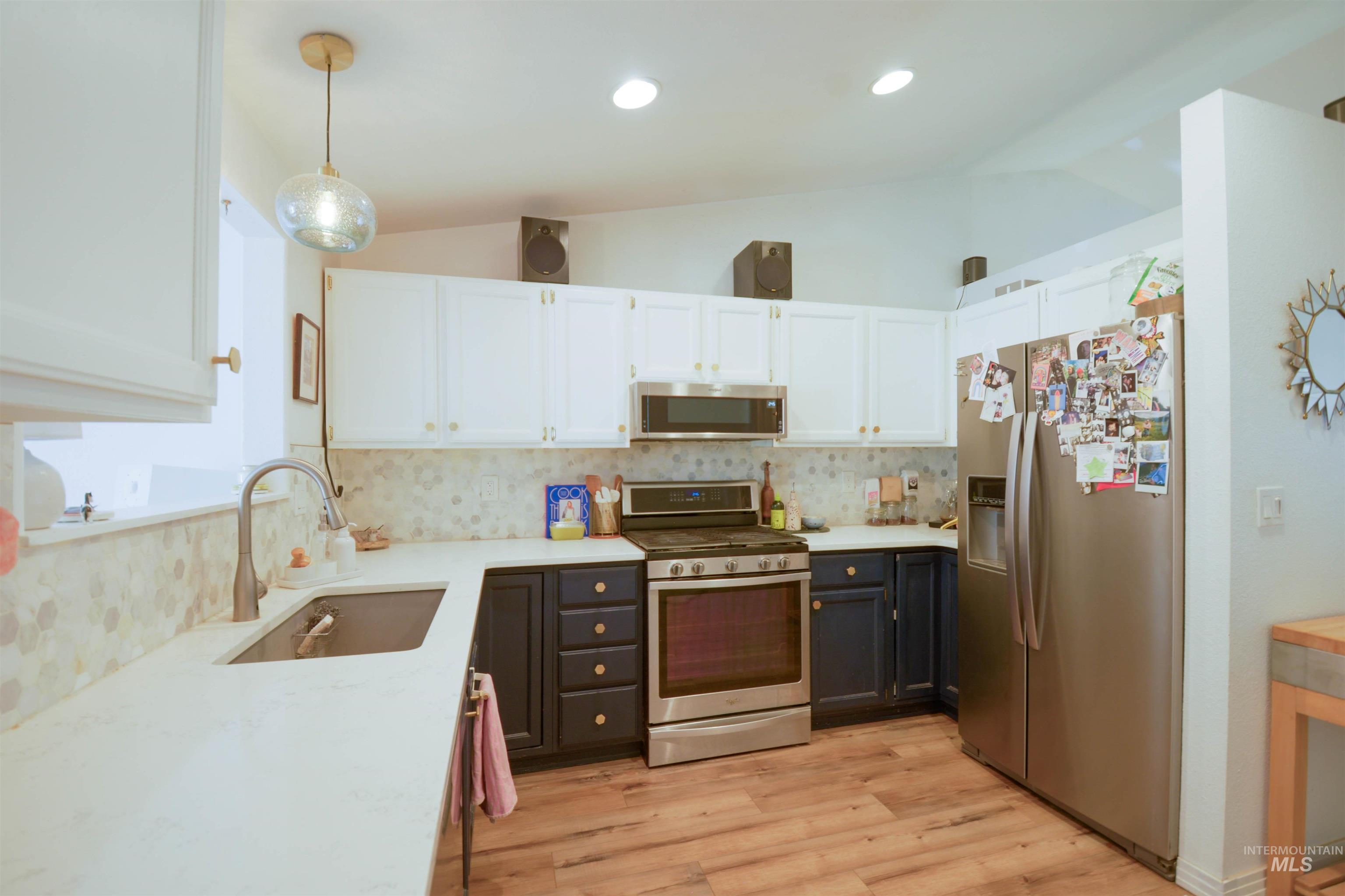 Kitchen with white cabinetry, lofted ceiling, appliances with stainless steel finishes, pendant lighting, and tasteful backsplash