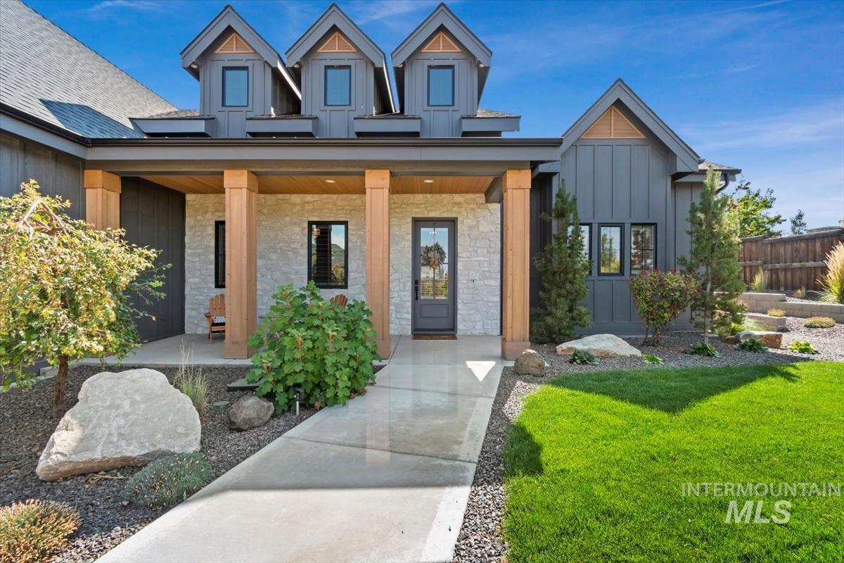 Property entrance featuring board and batten siding, a porch, stone siding, and a lawn