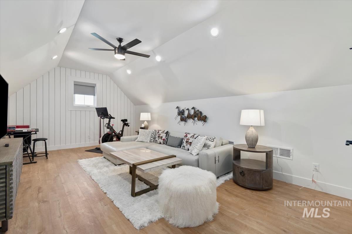 Living room with light wood-style floors, vaulted ceiling, recessed lighting, and a ceiling fan