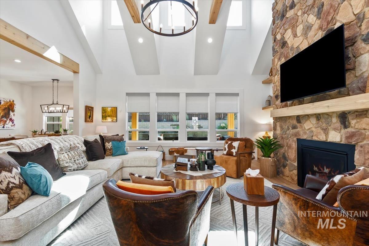 Living area with a chandelier, a stone fireplace, high vaulted ceiling, recessed lighting, and wood finished floors
