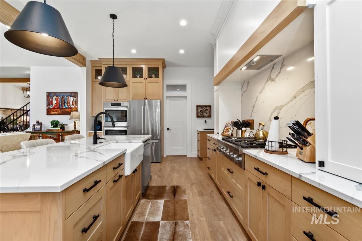 Kitchen featuring light brown cabinets, light wood-style floors, light stone counters, appliances with stainless steel finishes, and recessed lighting
