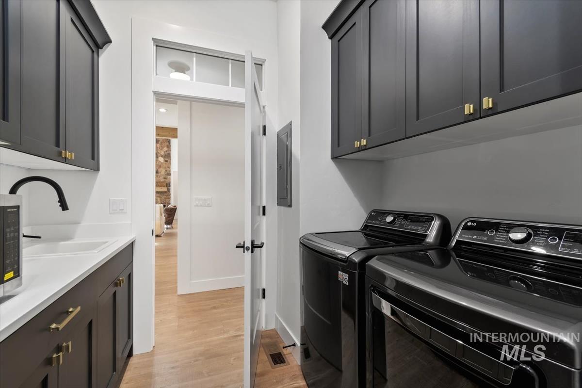 Laundry room featuring cabinet space, separate washer and dryer, and light wood finished floors