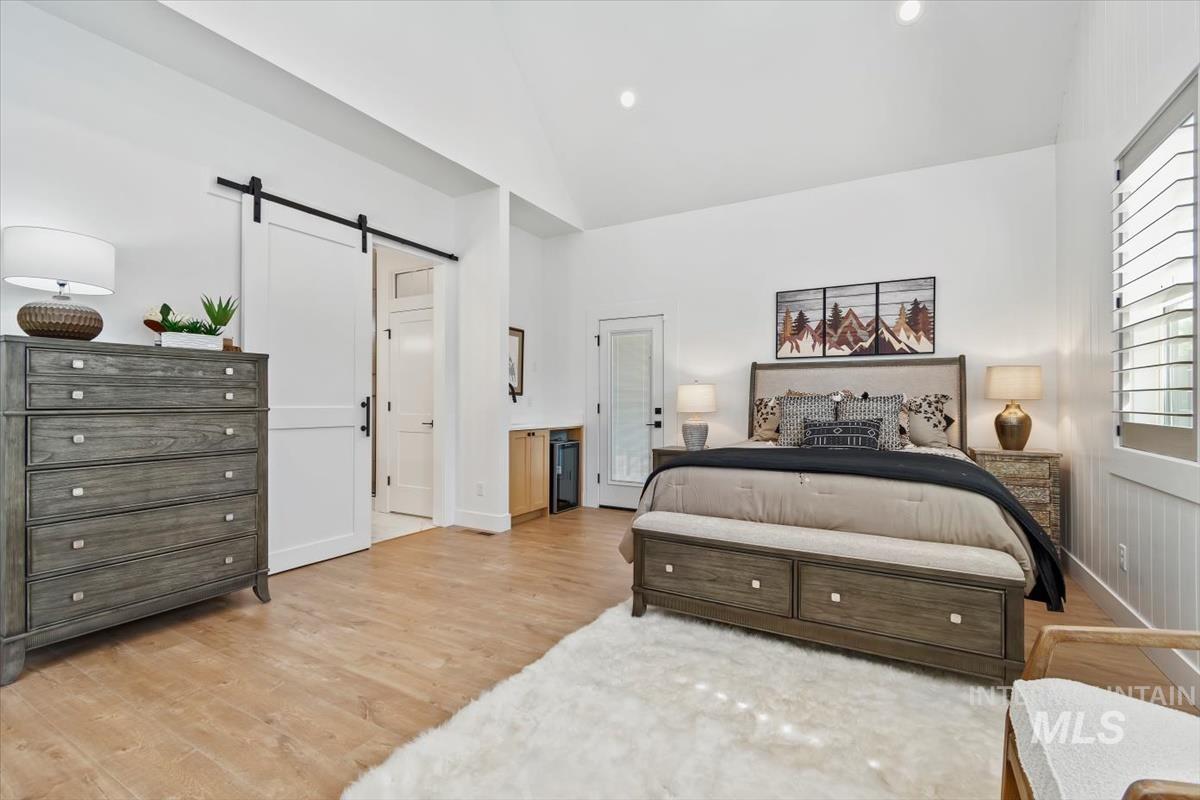 Bedroom with a barn door, light wood-style flooring, and recessed lighting