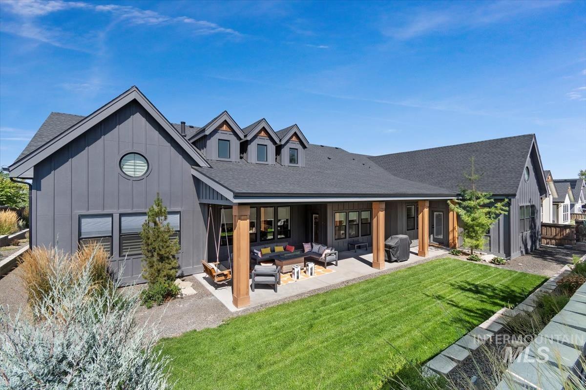 Rear view of house with an outdoor living space, board and batten siding, a lawn, and a shingled roof