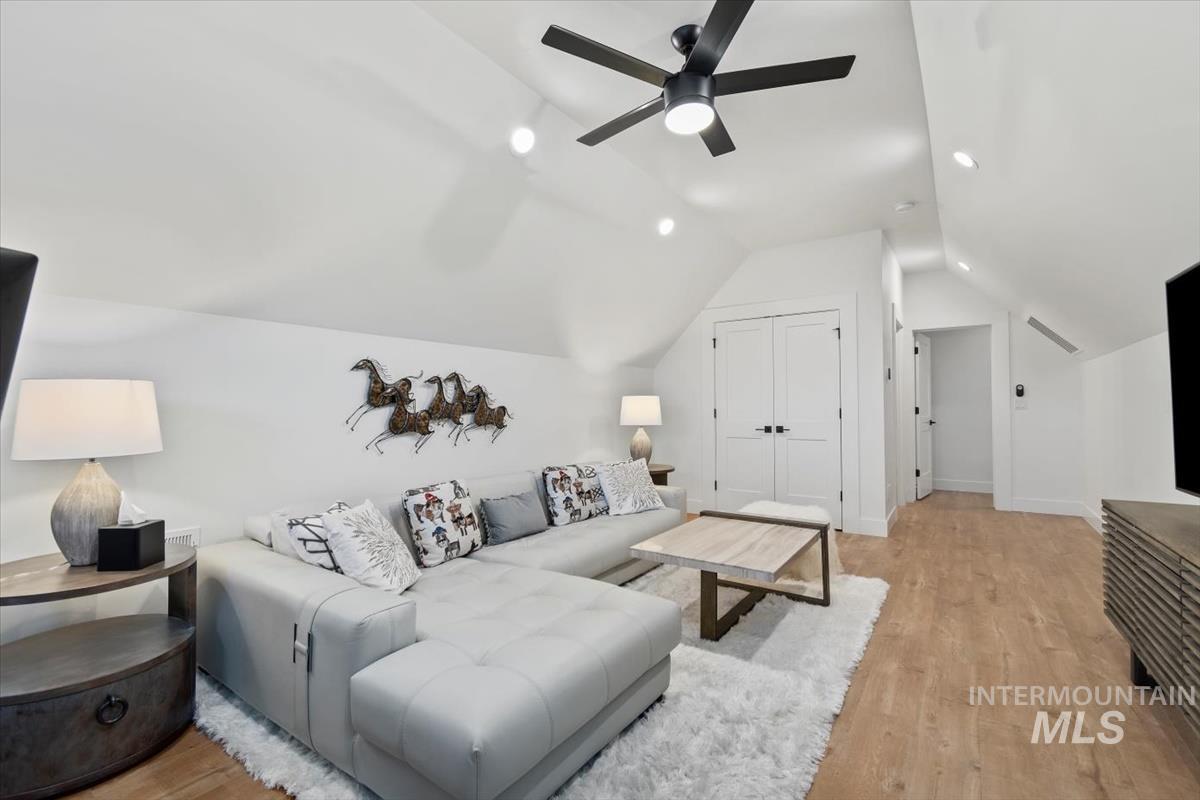 Living area with light wood finished floors, recessed lighting, and lofted ceiling