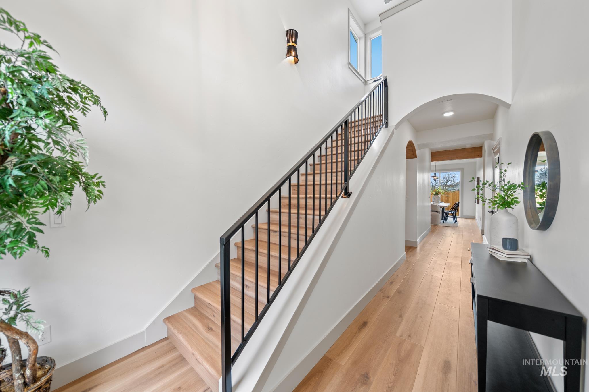 Staircase featuring arched walkways, wood finished floors, and a towering ceiling
