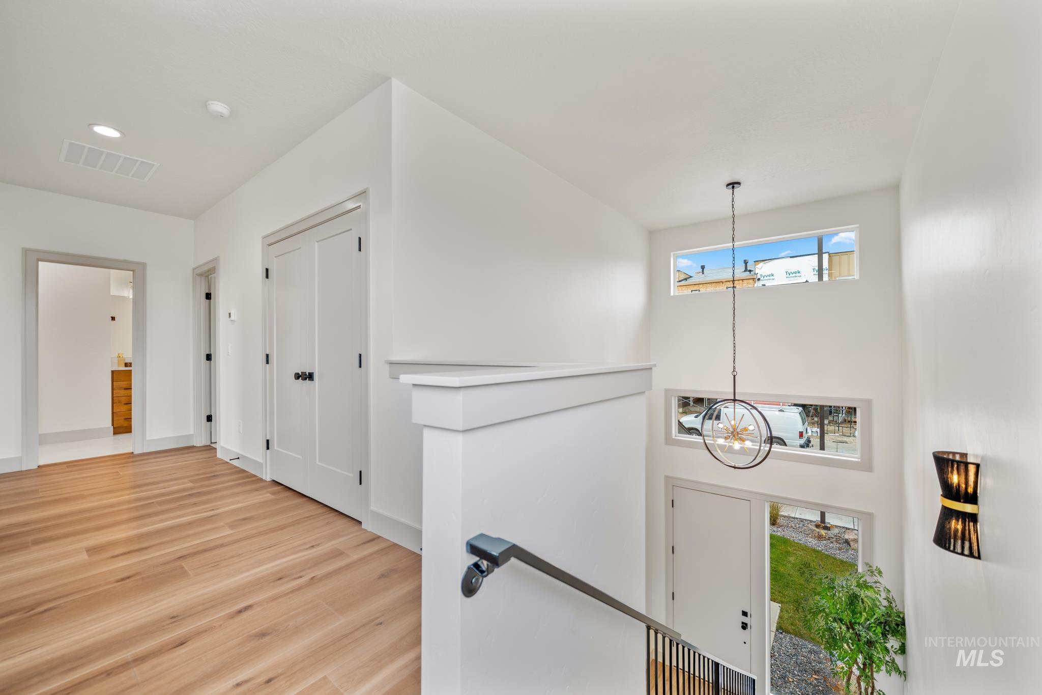 Corridor with plenty of natural light, a chandelier, an upstairs landing, and wood finished floors