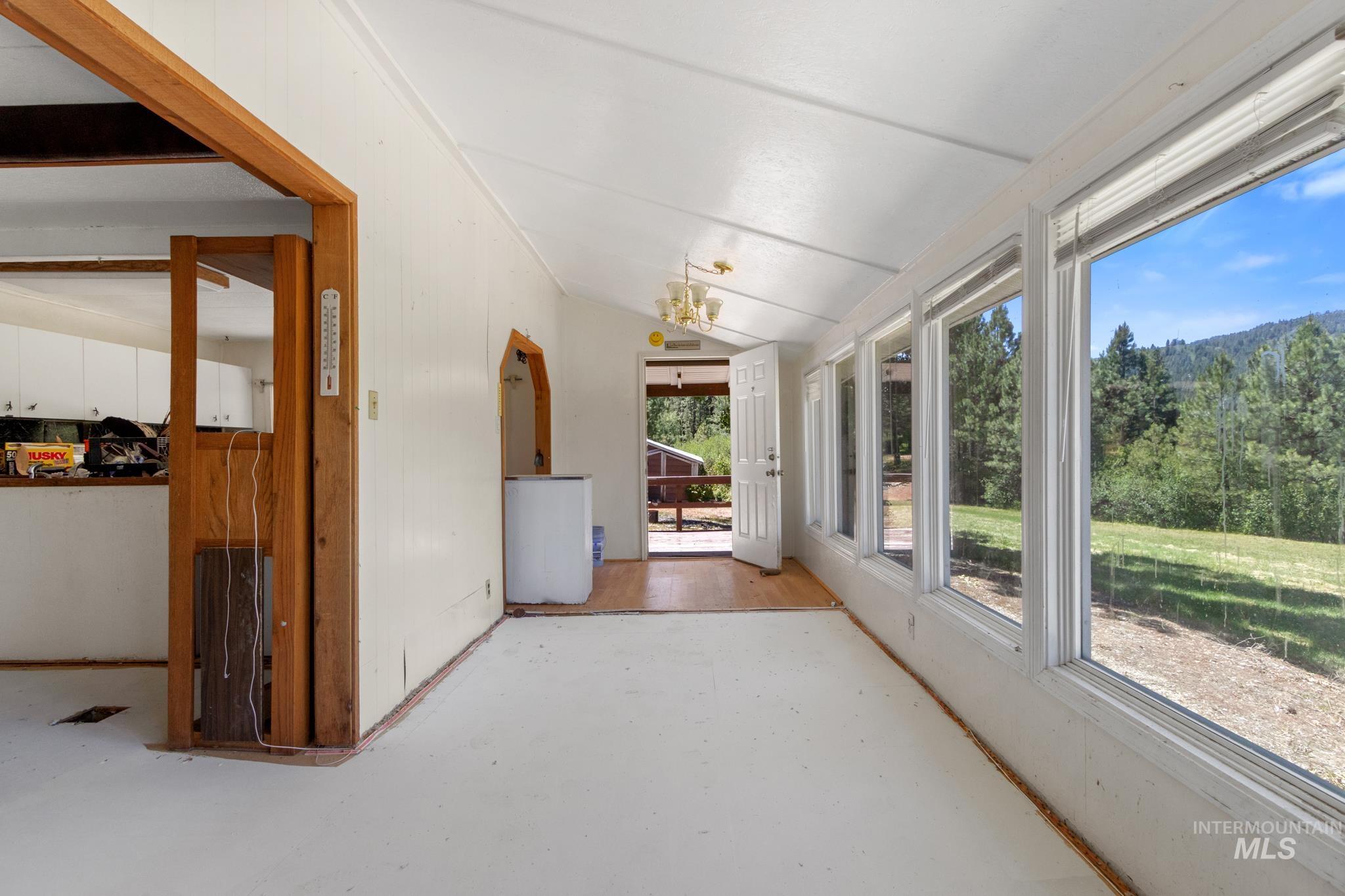 Sunroom featuring multiple large windows, wood-finish flooring, and white wall panels