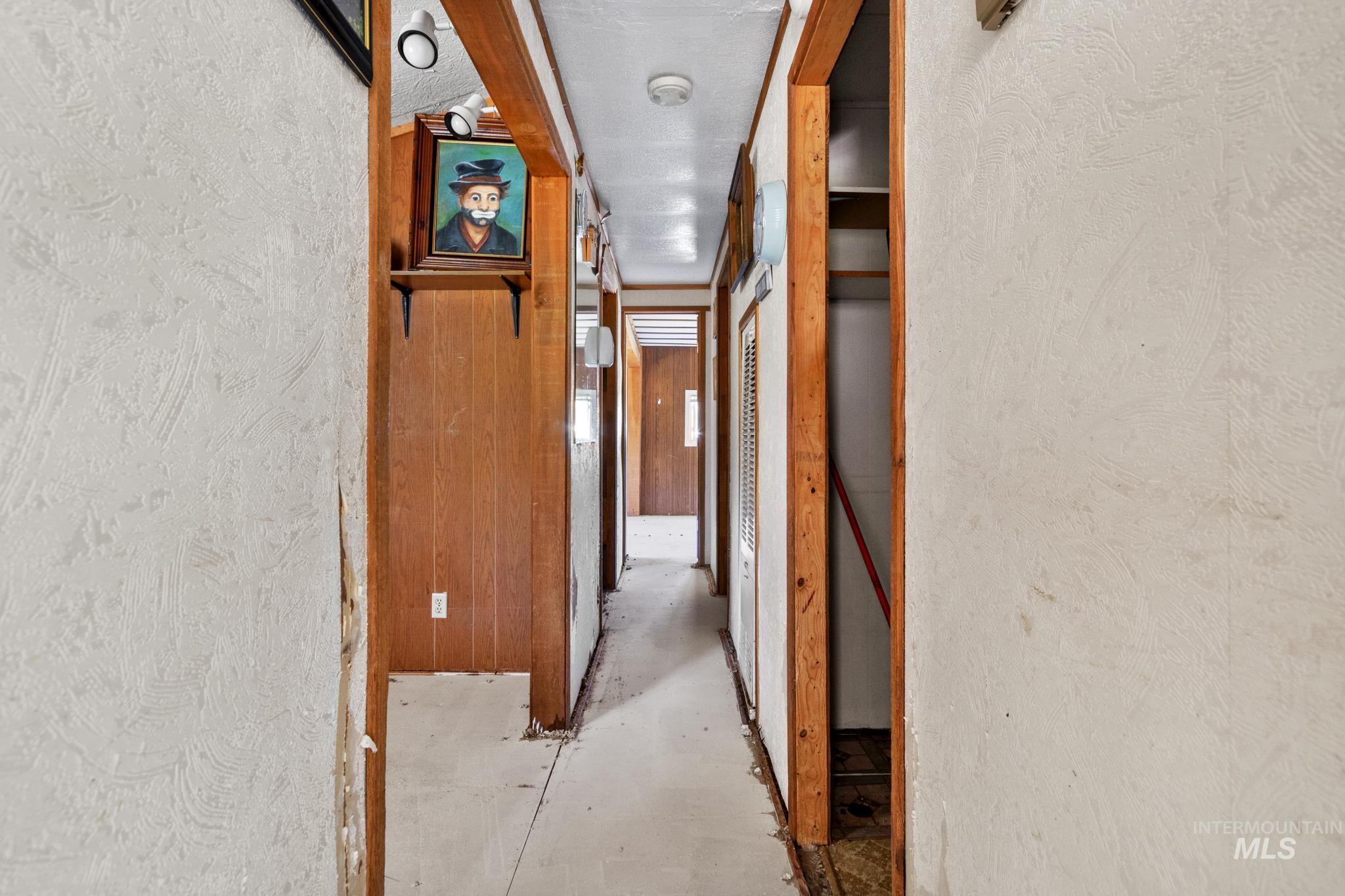 Hallway featuring wood paneling, wood-frame doorways, and textured wall surfaces
