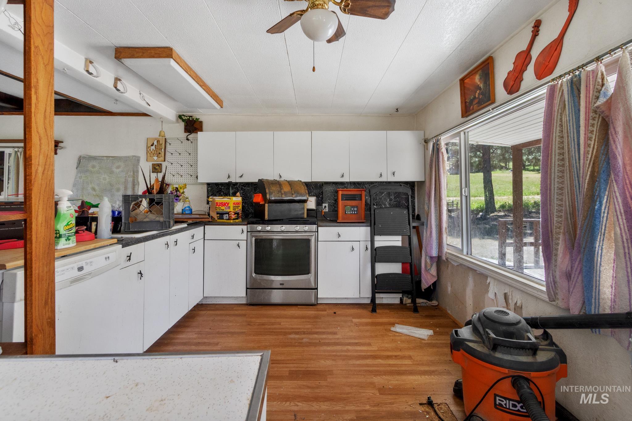 Kitchen featuring wood-finish flooring, white cabinetry, a stainless steel range, and a large window