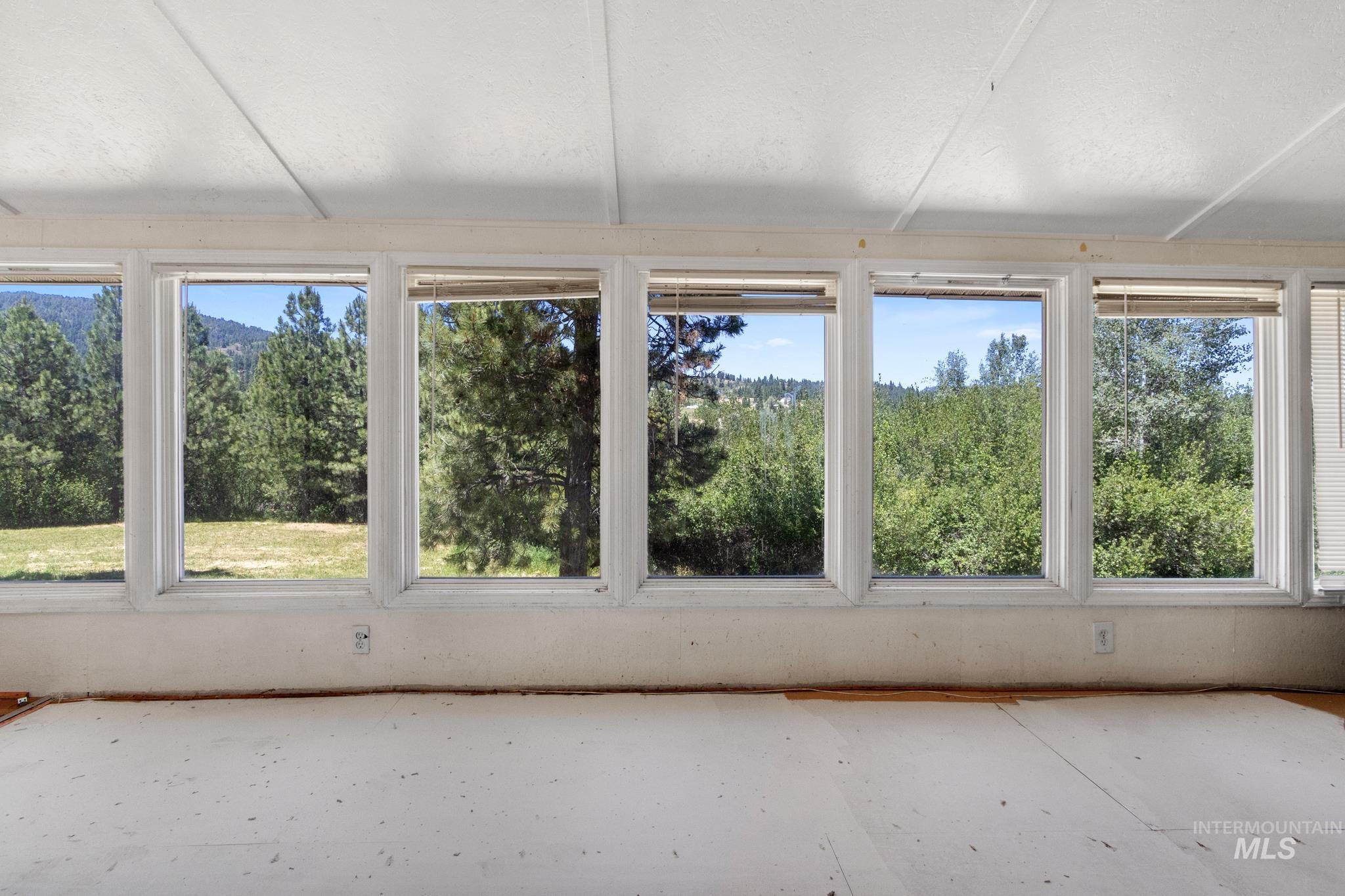 Sunroom featuring a wall of multiple windows, a white ceiling, and unfinished flooring