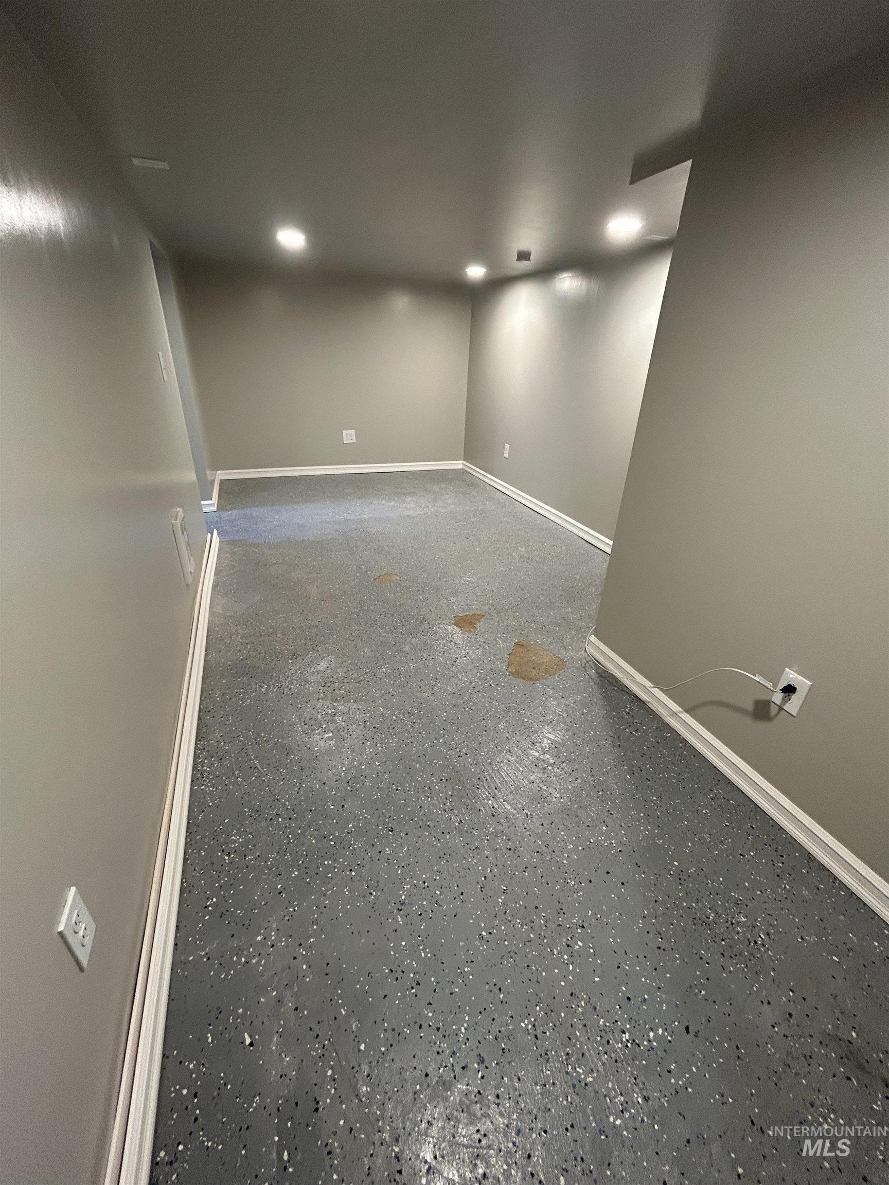 Finished room featuring gray walls, recessed lighting, and a speckled gray epoxy floor